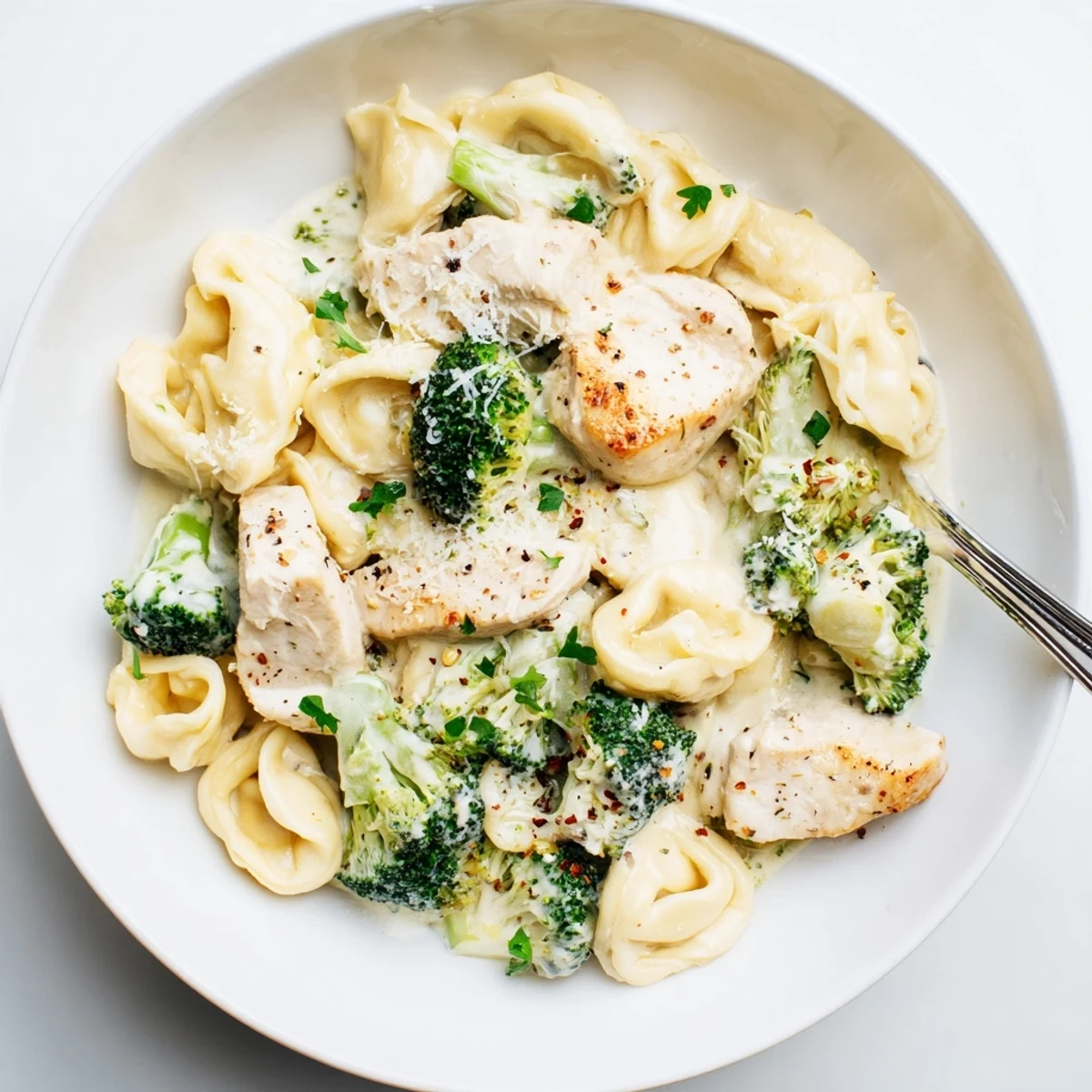 Skillet-tossed and saucy, Creamy Garlic Parmesan Tortellini Chicken Broccoli Recipe garnished with parsley