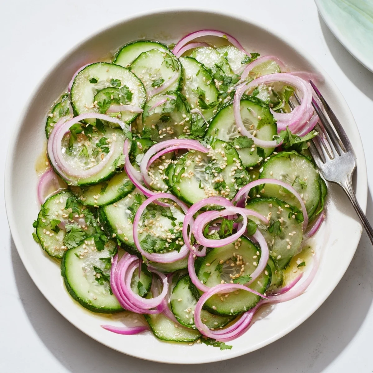 Glossy honey lime cucumber salad topped with cilantro in a white bowl for a light summer side
