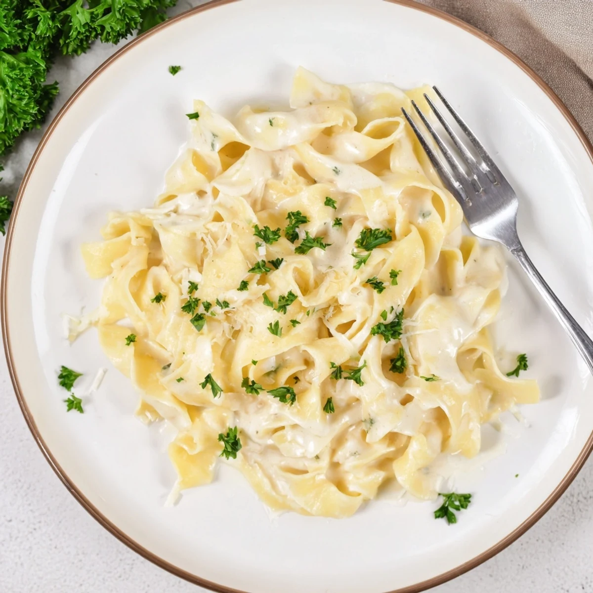 Golden wide egg noodles coated in a rich creamy Parmesan sauce with fresh parsley garnish