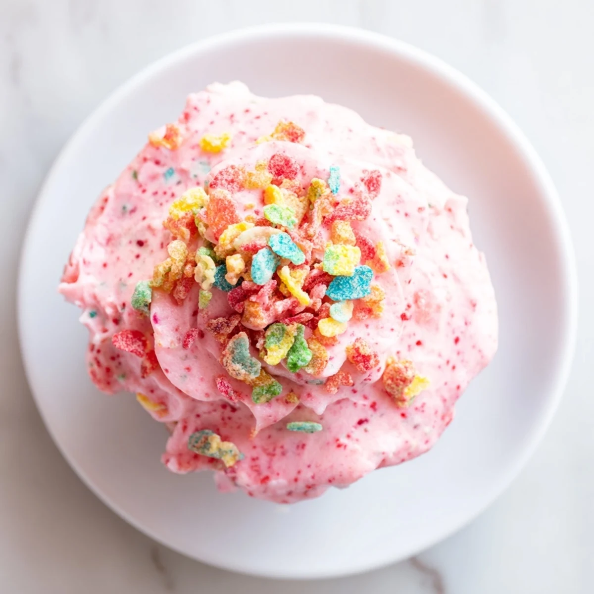 Vibrant Fruity Pebbles cereal frosting piped onto cupcakes topped with colorful cereal pieces