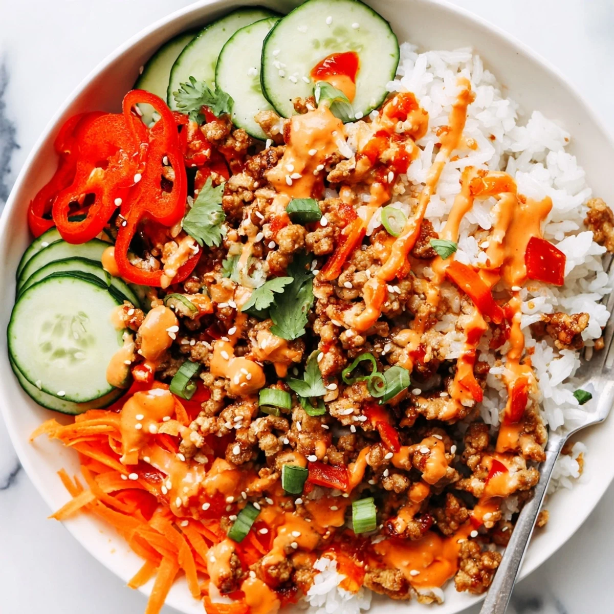 Seasoned ground turkey piled over fluffy rice topped with vibrant crunchy vegetables and Bang Bang sauce