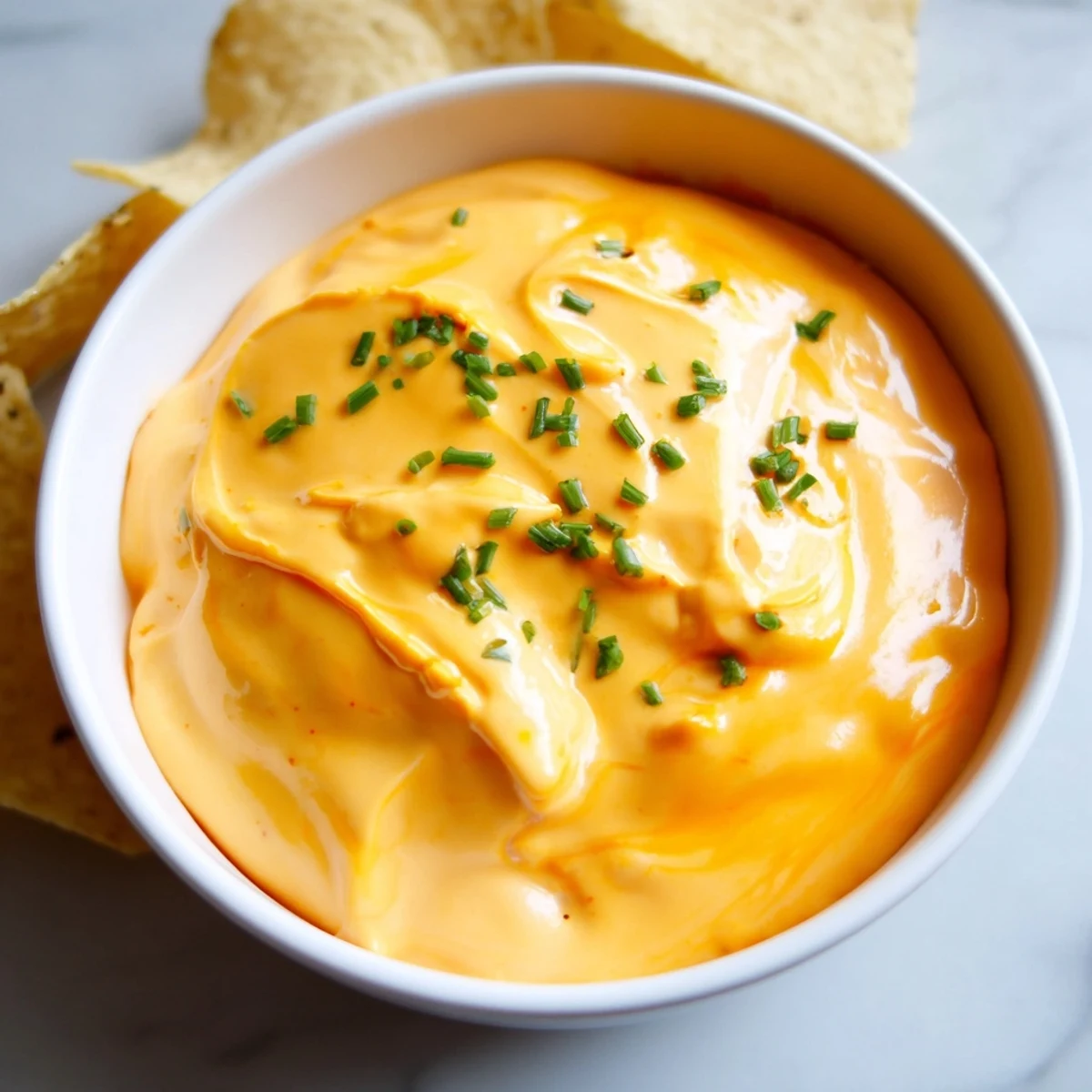 Warm, gooey cheese dip in a rustic bowl surrounded by golden tortilla chips.