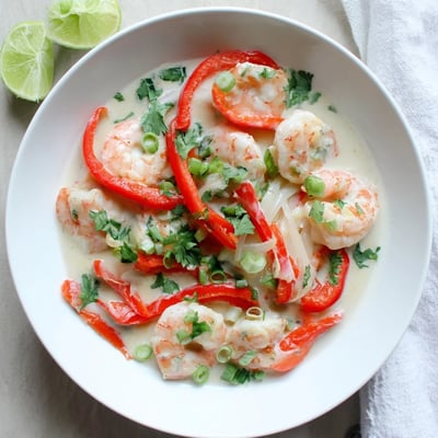 A close-up of Creamy Coconut Shrimp Buffet Style over white rice, with red bell peppers visible in the sauce.